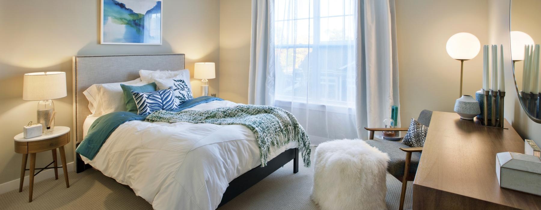 a bedroom with a bed, large window and a desk