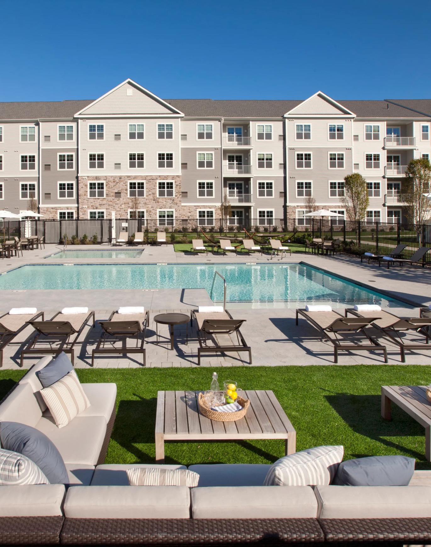 a pool with chairs and tables by it and a building in the background