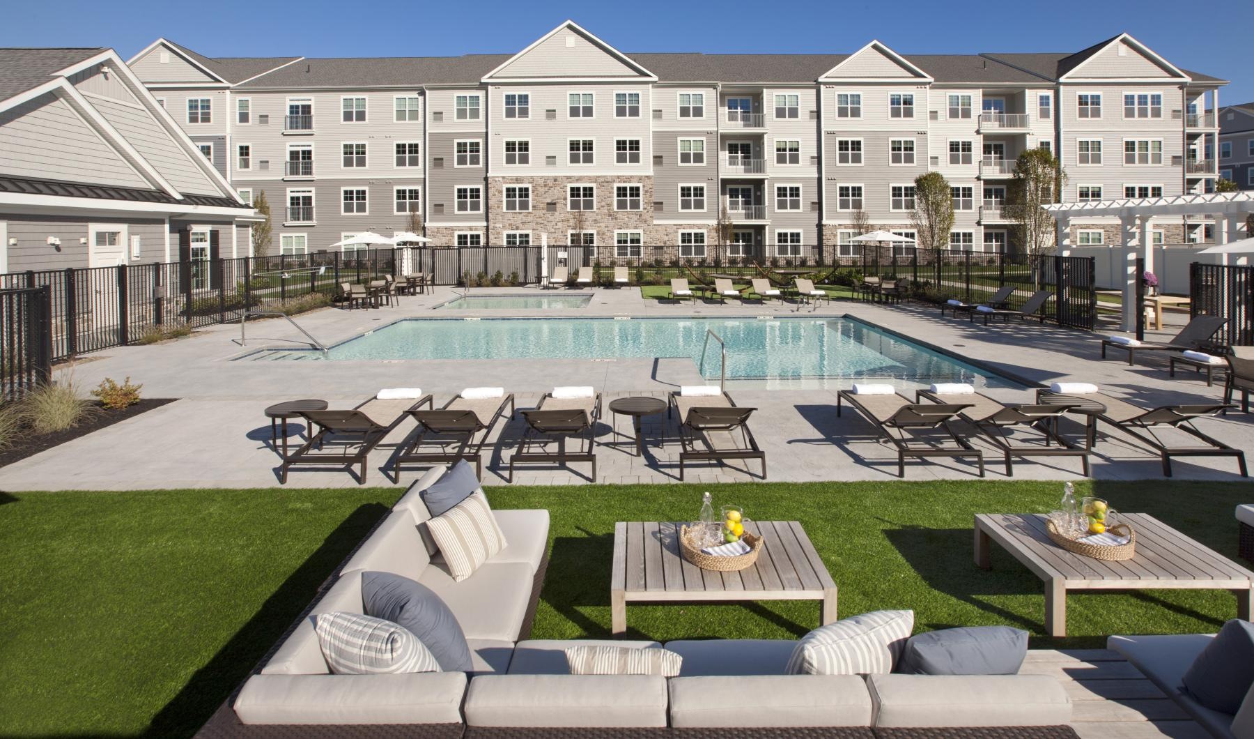 a pool with chairs and tables by it and a building in the background
